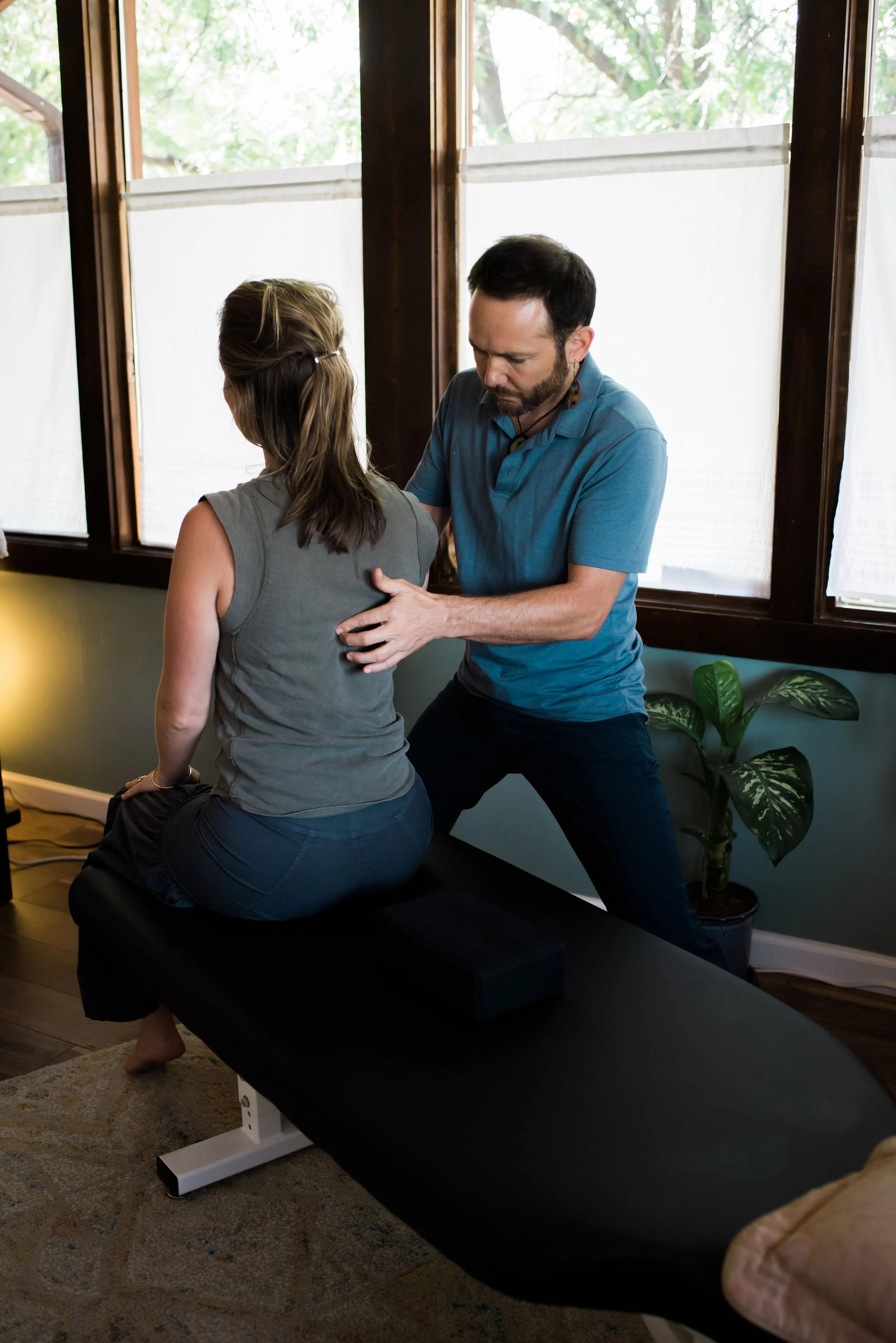 Dr. Dylan performing a chiropractic adjustment by a sunlit window