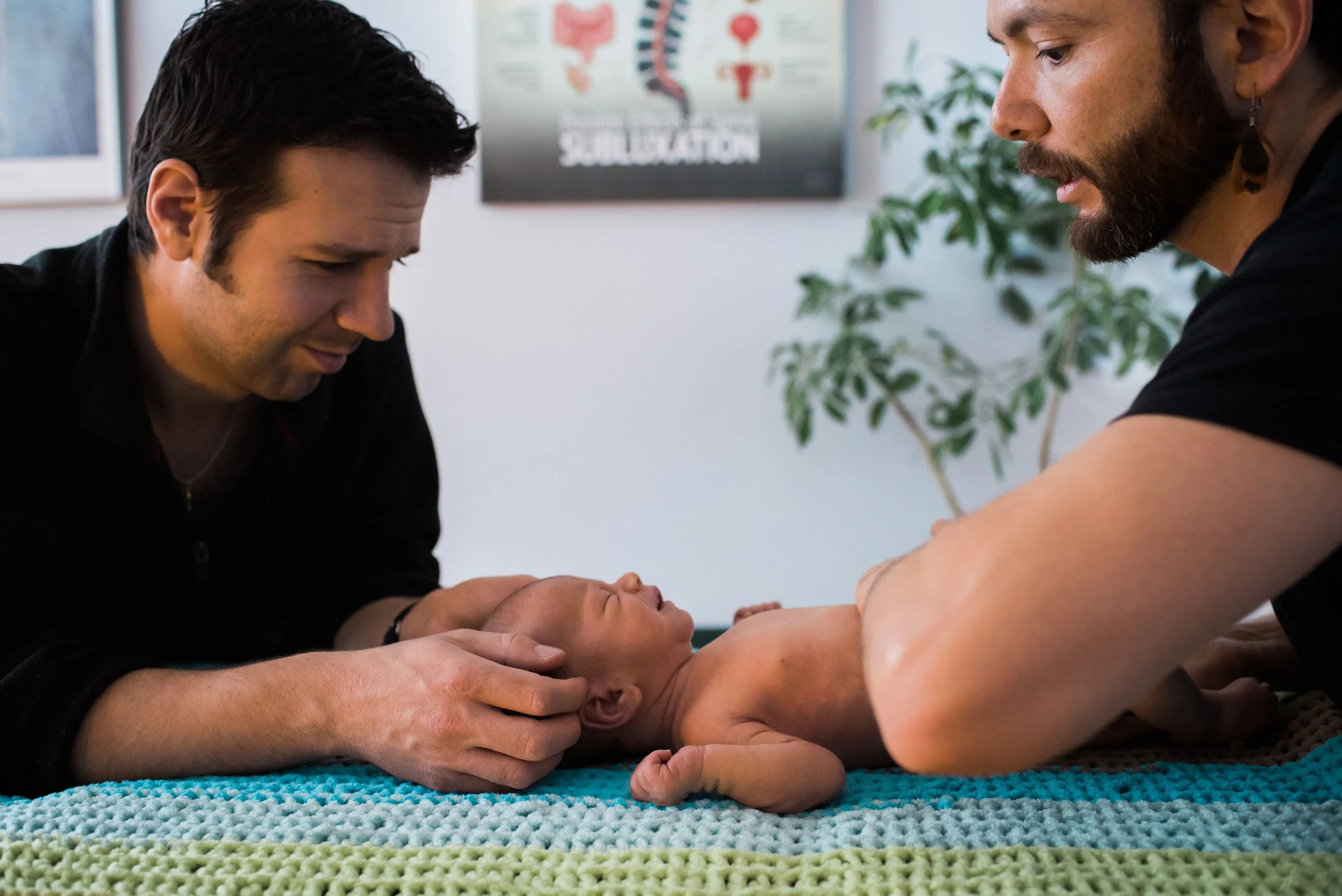 Newborn receiving gentle chiropractic adjustment with father's support
