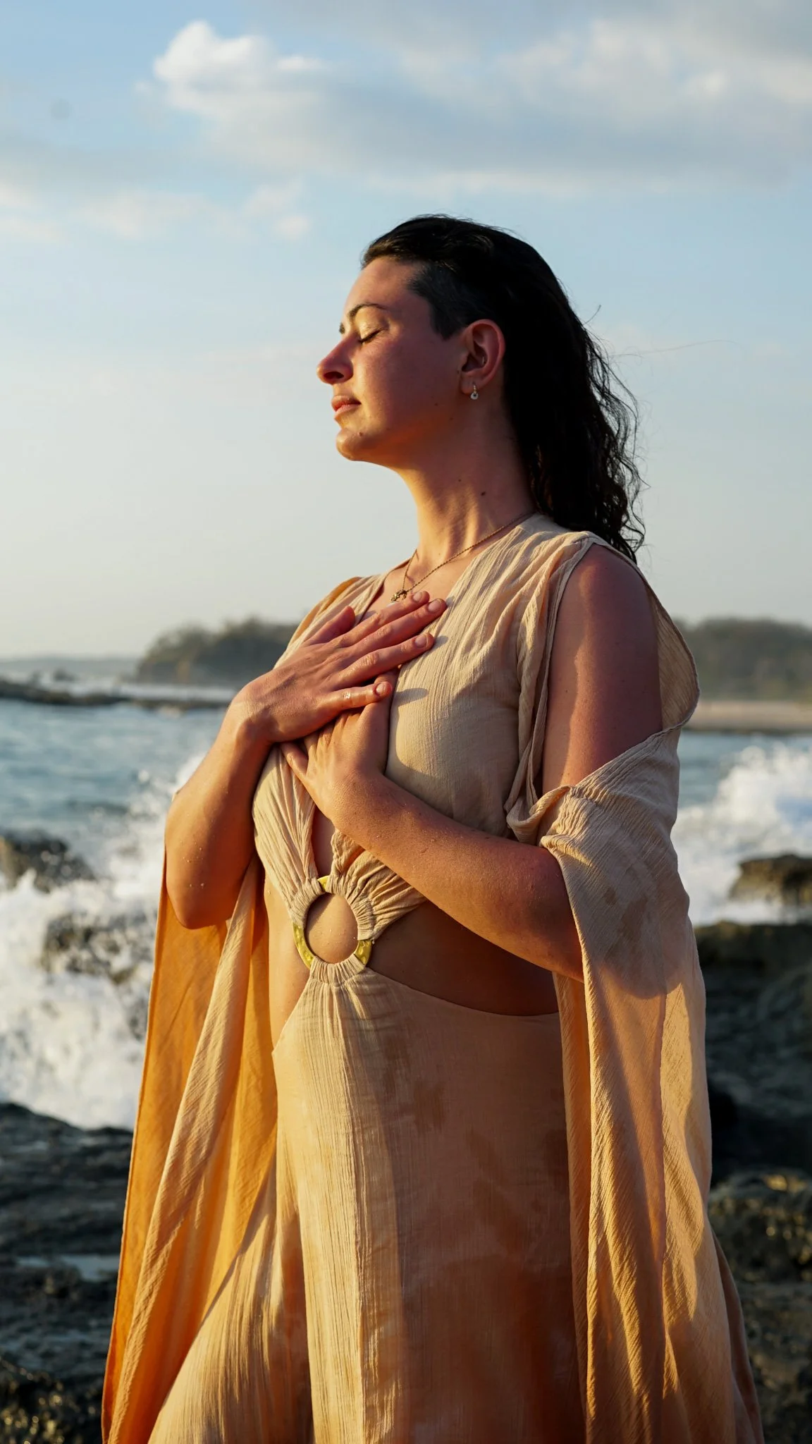 Ra Jonlynn at the ocean with hands over her heart